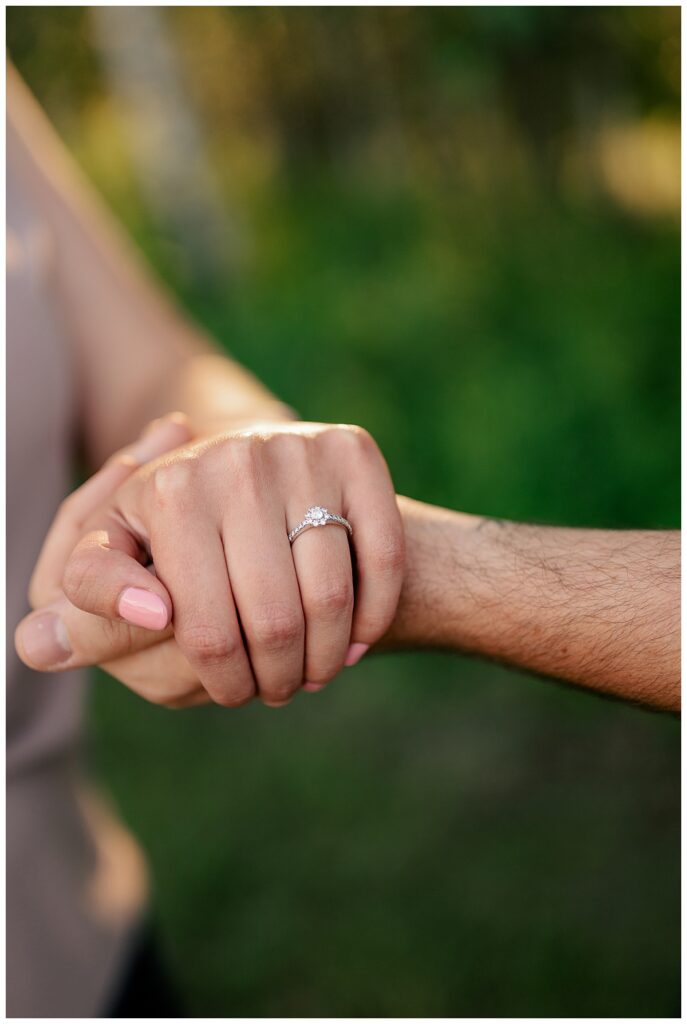 woman places hand on man's to show off ring at Quarry Park evening engagement session 