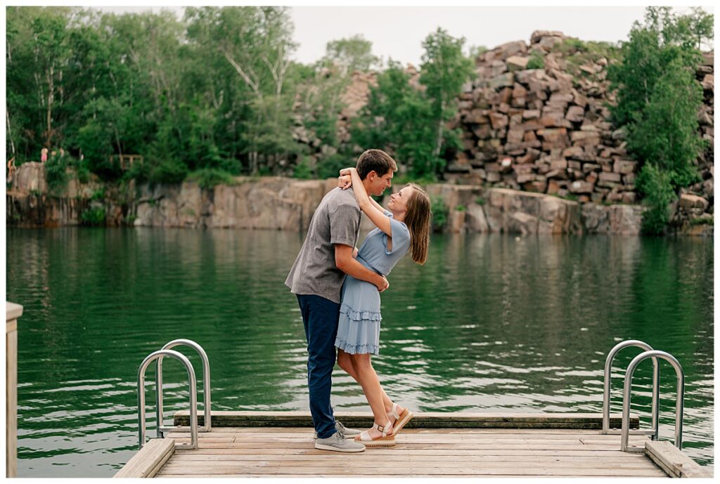 engaged couple wrap arms around each other in front of reflecting pond by Minnesota wedding photographer