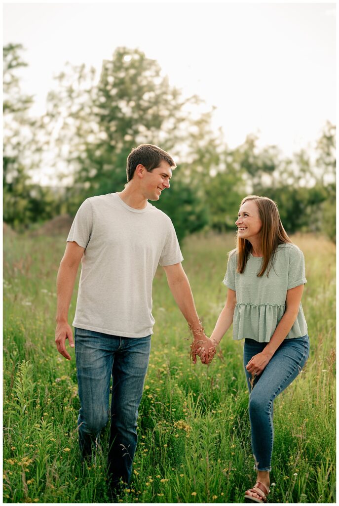 couple walks through meadow hand in hand by Rule Creative Co