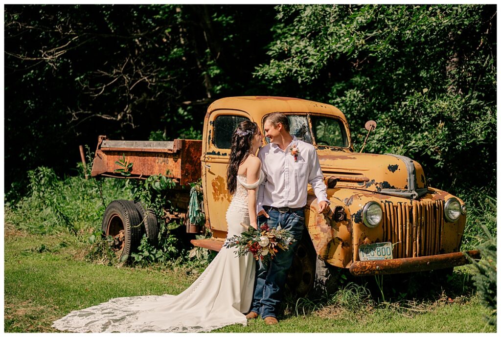 couple stands by old truck by Minnesota wedding photographer