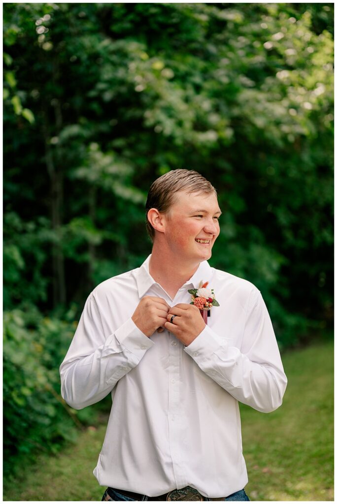 groom adjusts buttons on his shirt by Rule Creative Co