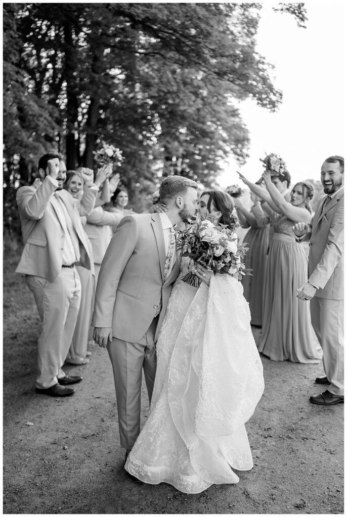 bridal party cheers as couple kisses by Minnesota wedding photographer