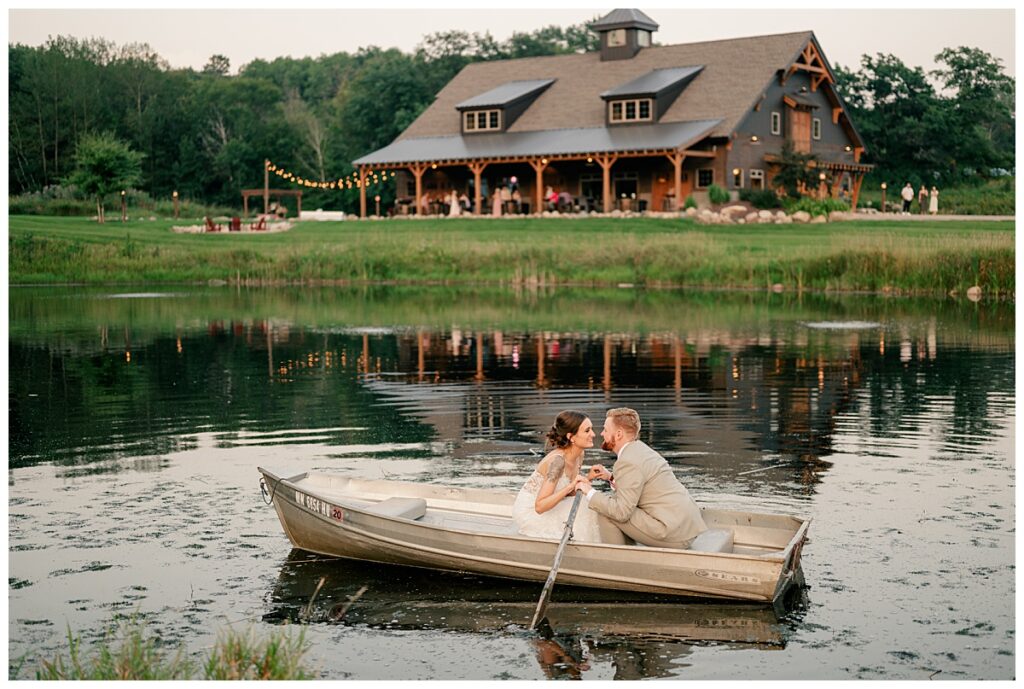 couple leans in close on a boar in front of wedding venue by Rule Creative Co