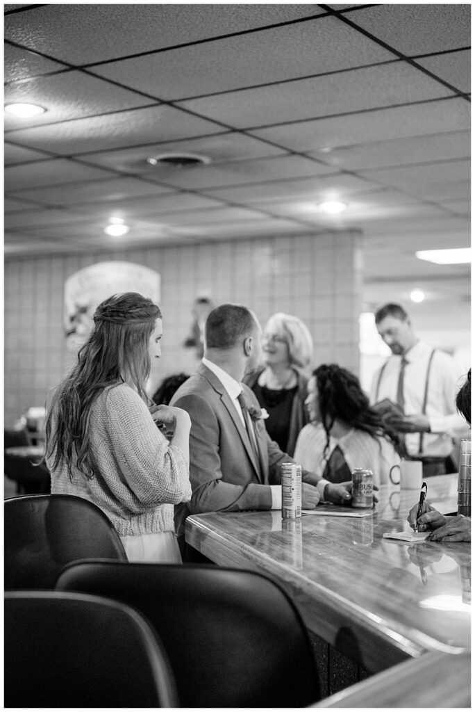 couple shares a drink at the bar with guests by Minnesota wedding photographer