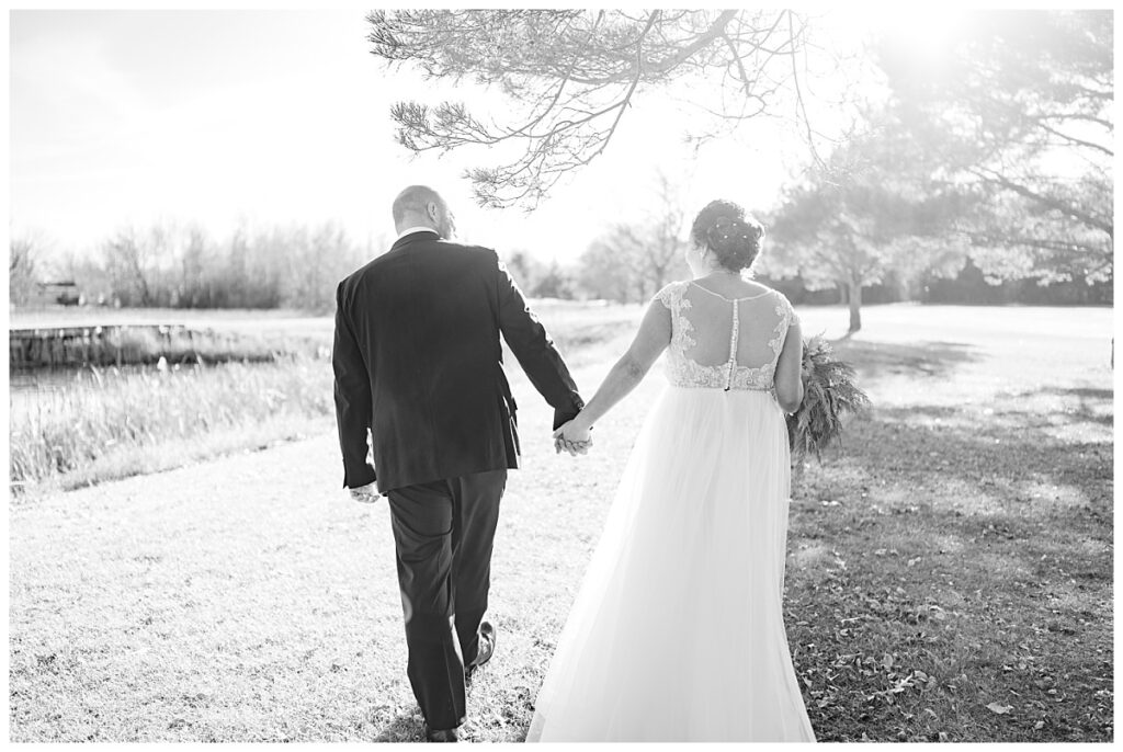 bride and groom walk hand in hand along path by Rule Creative Co