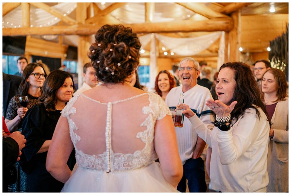 guests laugh and have expressive faces talking to the bride by Minnesota wedding photographer