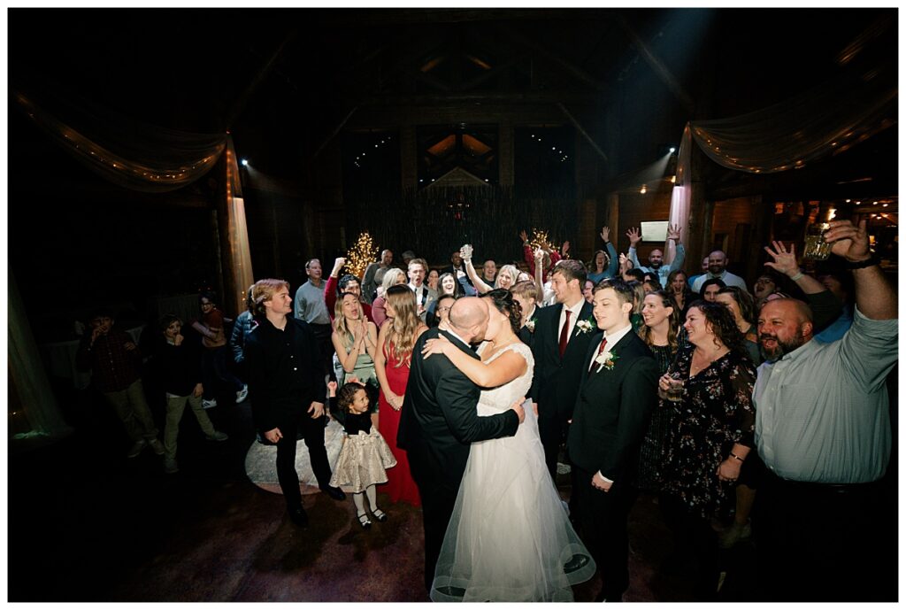 bride and groom kiss on dance floor as guests cheer by Rule Creative Co