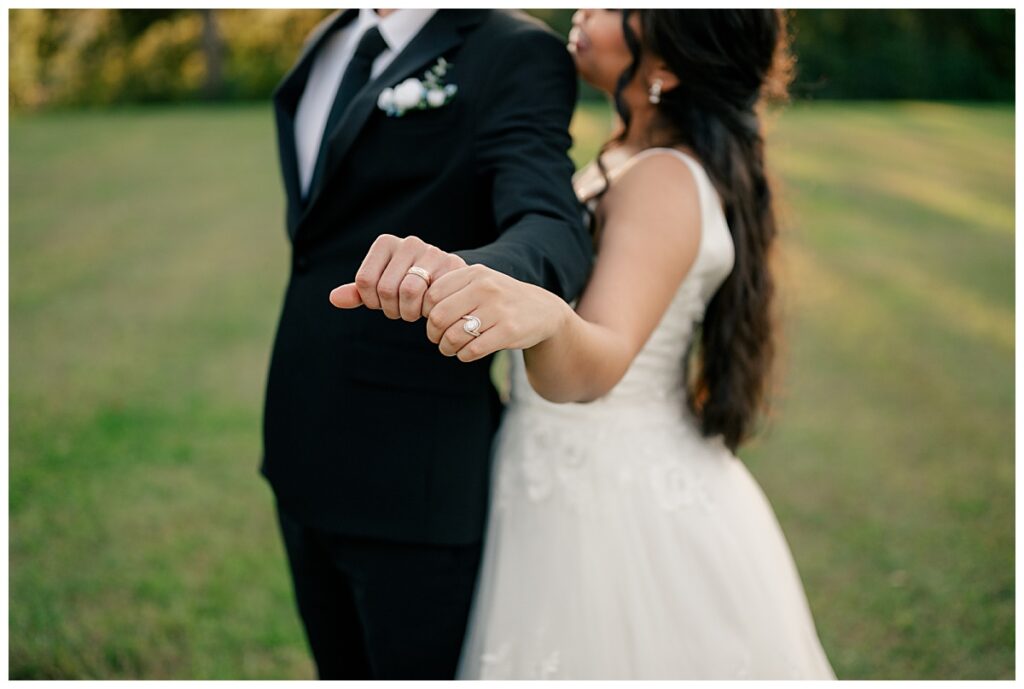 couple holds out hands together to show off new rings by Minnesota wedding photographer