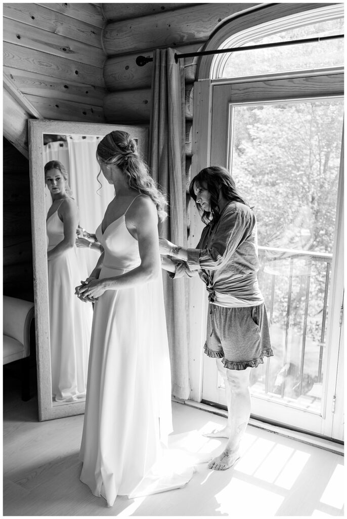 woman helps bride into her gown by Rule Creative Co