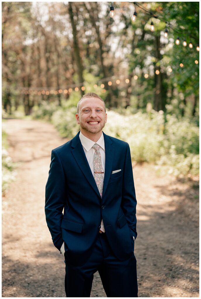 groom smiles with hands in his pockets by Minnesota wedding photographer