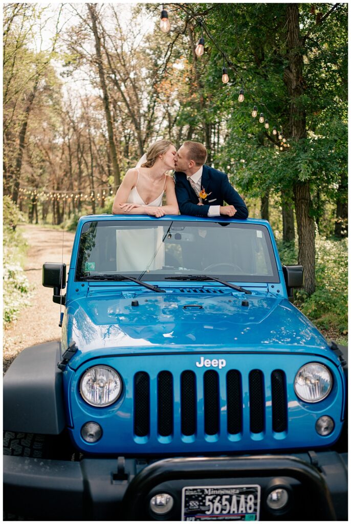 man and woman kiss standing up in a Jeep at Northern Oaks summer wedding