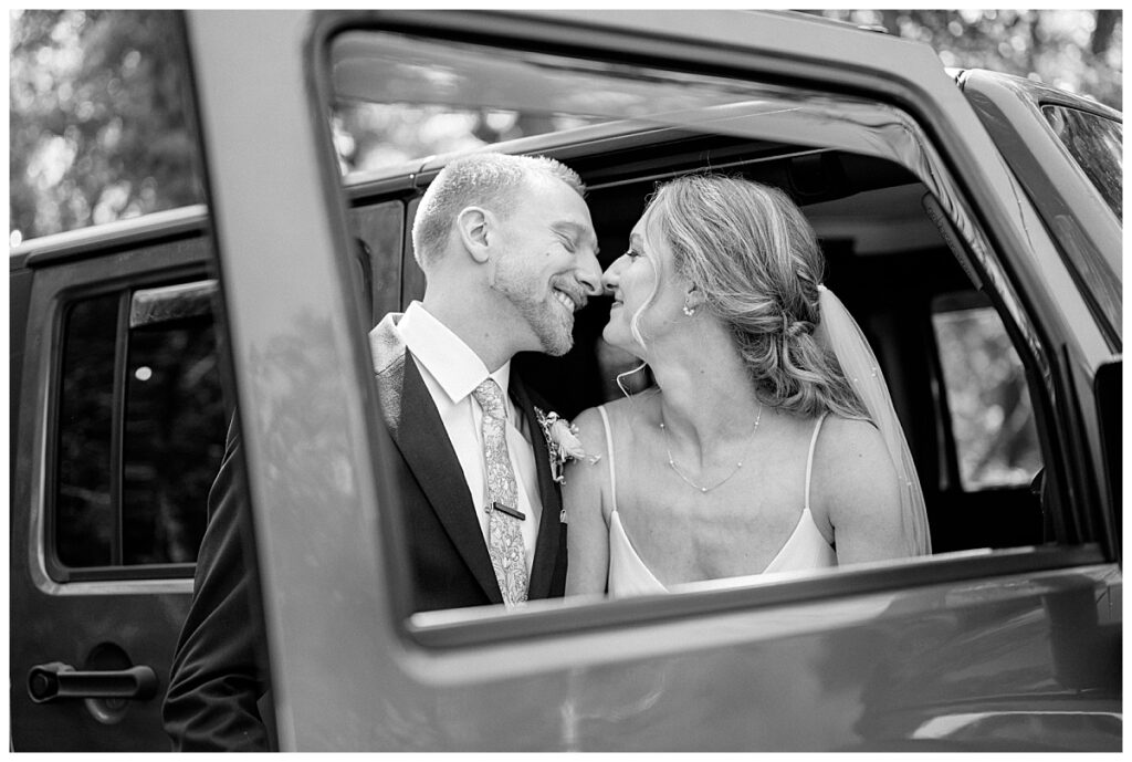 couple leans in for a kiss sitting in the front of a car by Minnesota wedding photographer