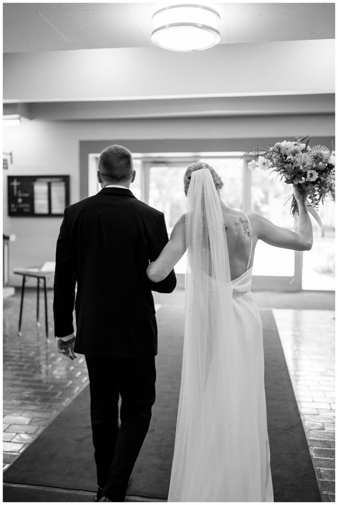 bride puts bouquet up in air as she walks out of ceremony with groom by Minnesota wedding photographer