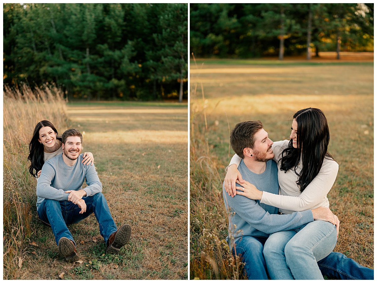 woman sits in fiancé's lap in field by Minnesota wedding photographer