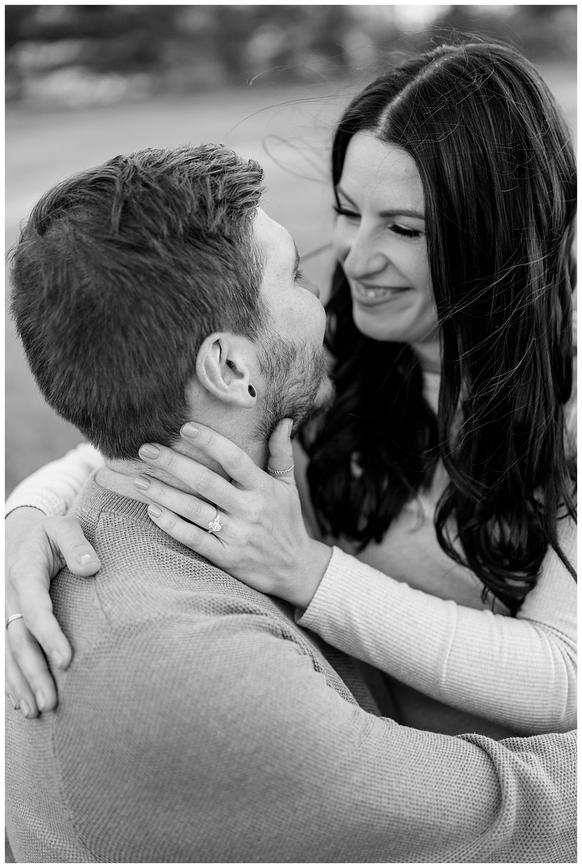 woman smiles at fiance as she holds his neck in Belle Prairie Park