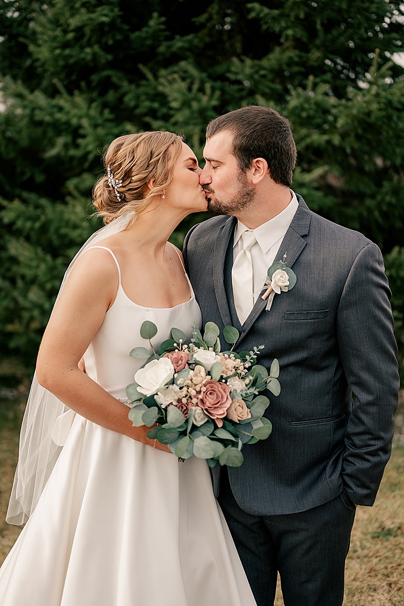 bride and groom share a kiss in the snow by Minnesota wedding photographer