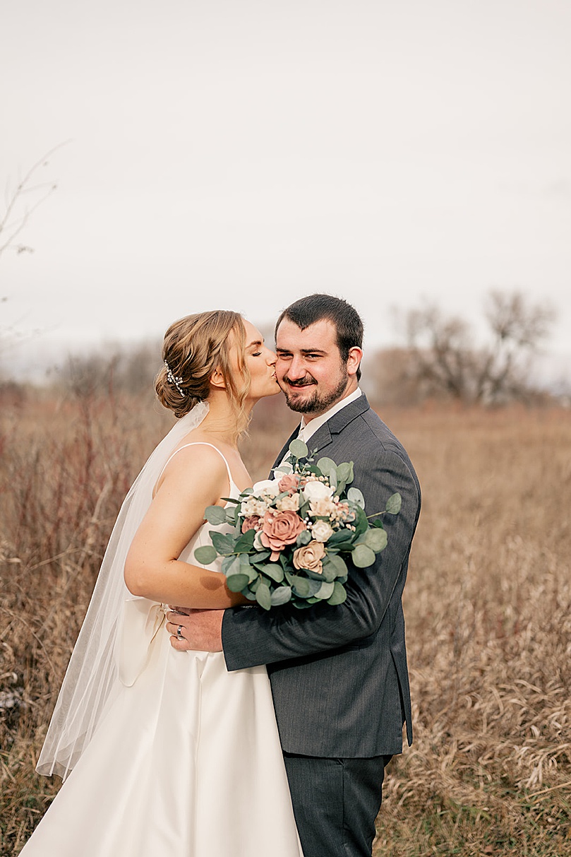 blonde kisses her fiancee cheek in field by Rule Creative Co