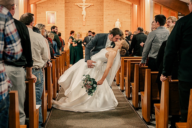 man dips new wife for a kiss in the aisle by Rule Creative Co