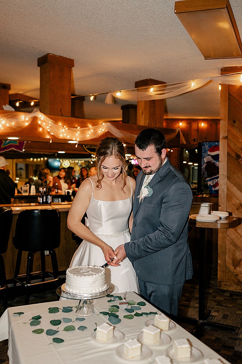 newlyweds cut a white cake together by Rule Creative Co