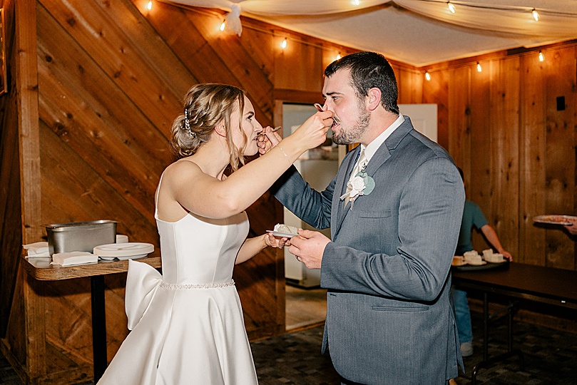 newlyweds fed each other cake by Minnesota wedding photographer