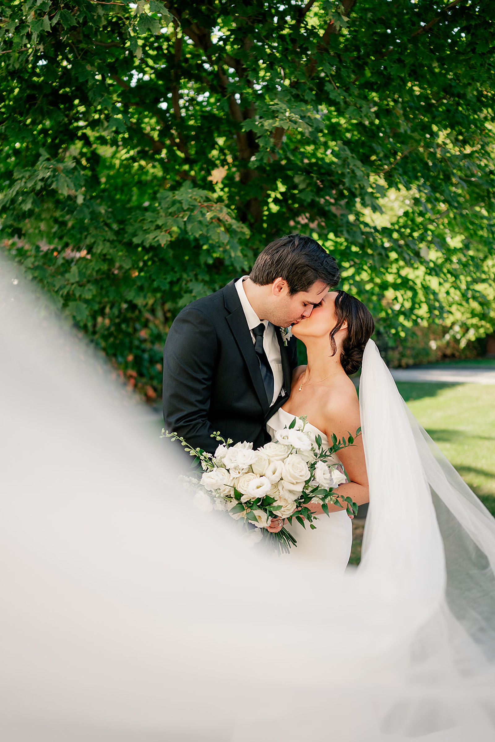 man and woman share kiss under white veil by Minnesota wedding photographer