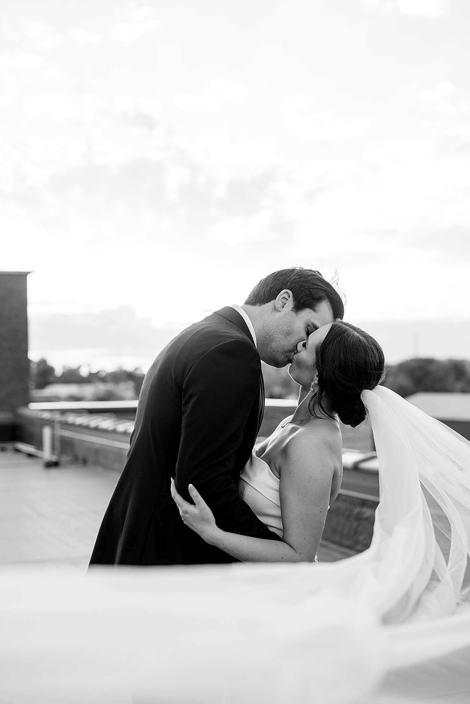 man and wife share a wind swept kiss on rooftop by Minnesota wedding photographer