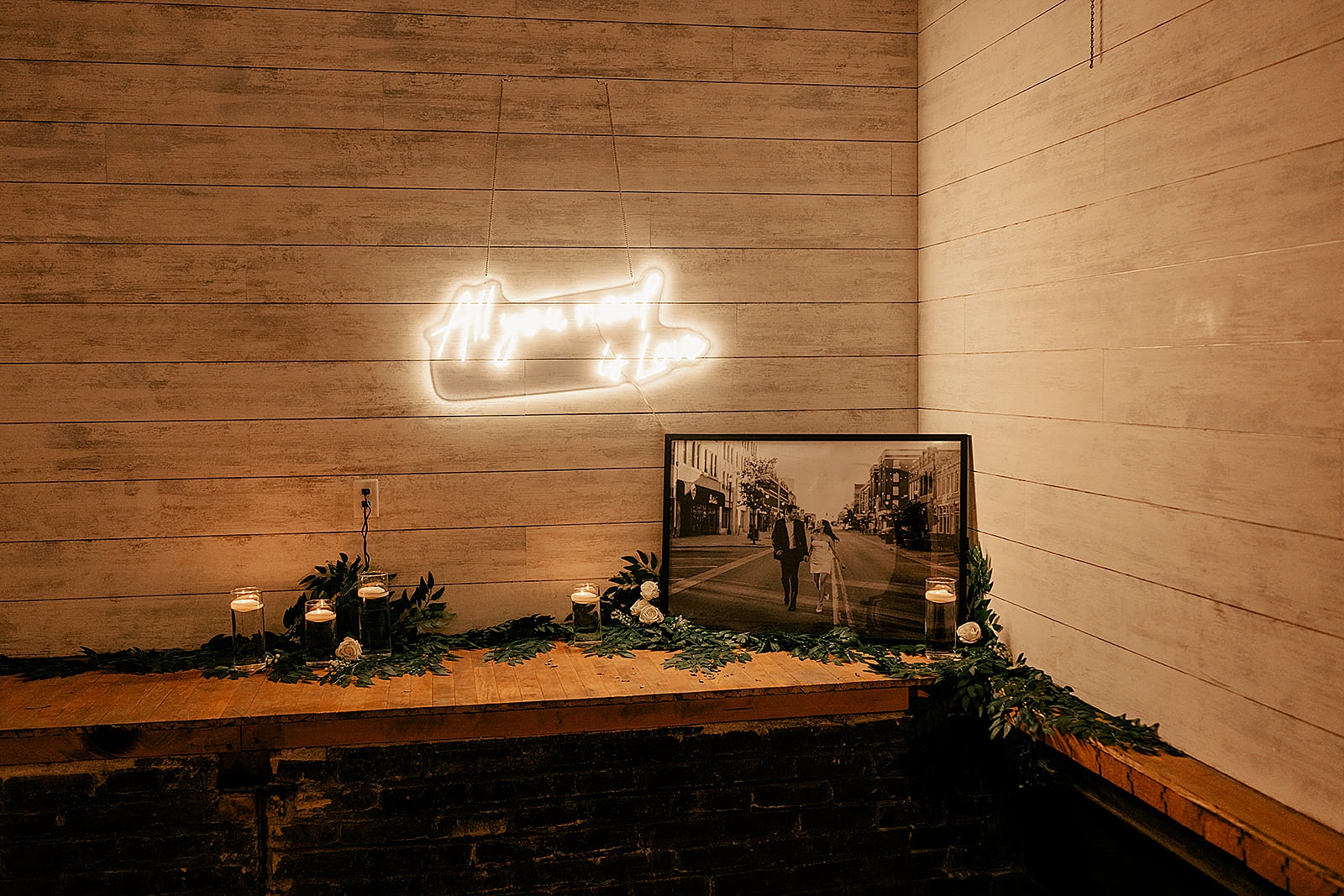 framed photos of newlyweds on bar with light up sign for Harvester Square wedding