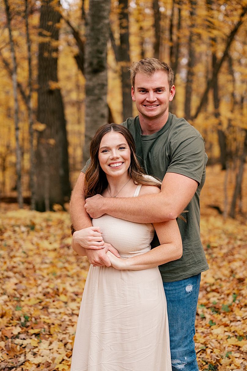 engaged couple embrace in trees by Minnesota wedding photographer