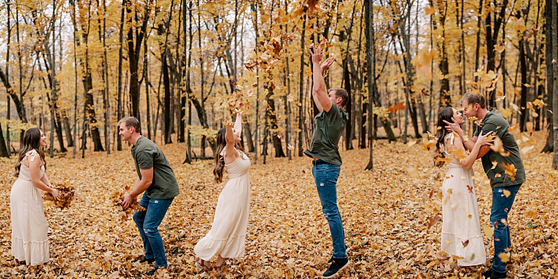 man and woman throw fall leaves in the air together for rainy day engagement photos