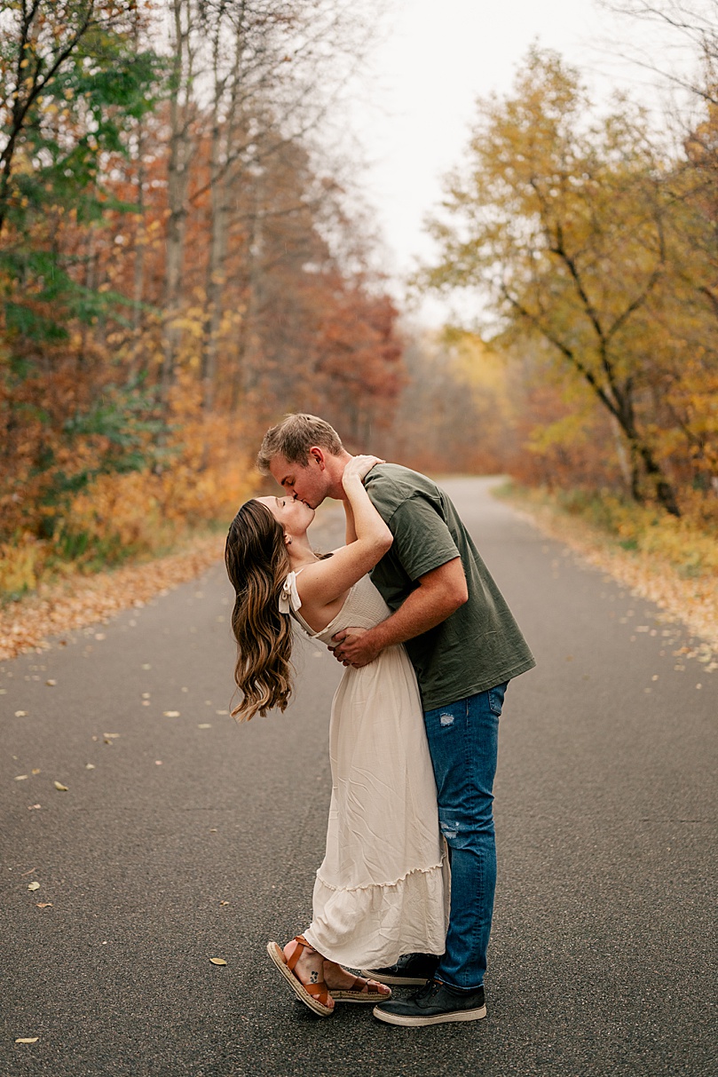 man kisses his woman in the street under fall leaves by Rule Creative Co