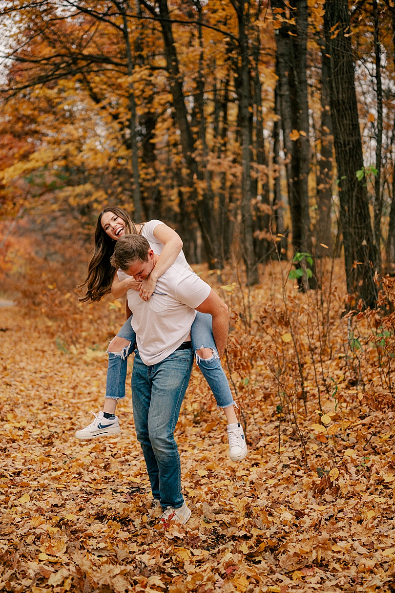 woman hops on mans back laughing  by Minnesota wedding photographer