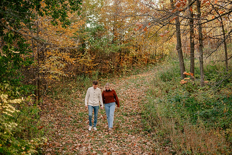 couple walk through trees for golden hour arboretum engagement session