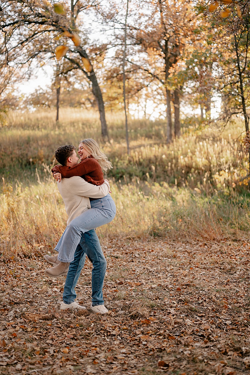 man spins his wife-to-be in field by Minnesota wedding photographer