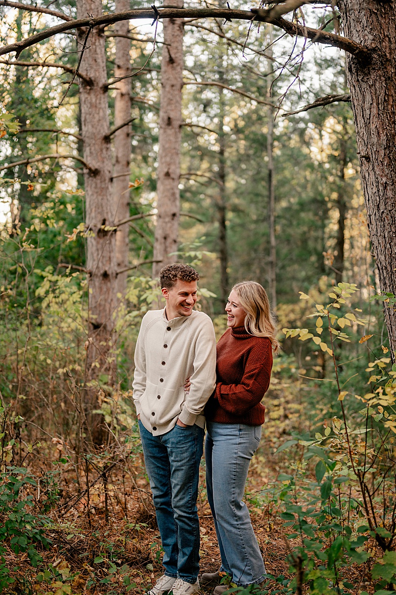 engaged couple embrace and laugh in woods by Rule Creative Co