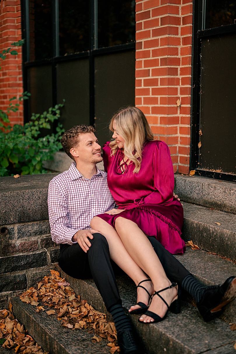 woman in pink dress sits on mans lap on steps by Minnesota wedding photographer