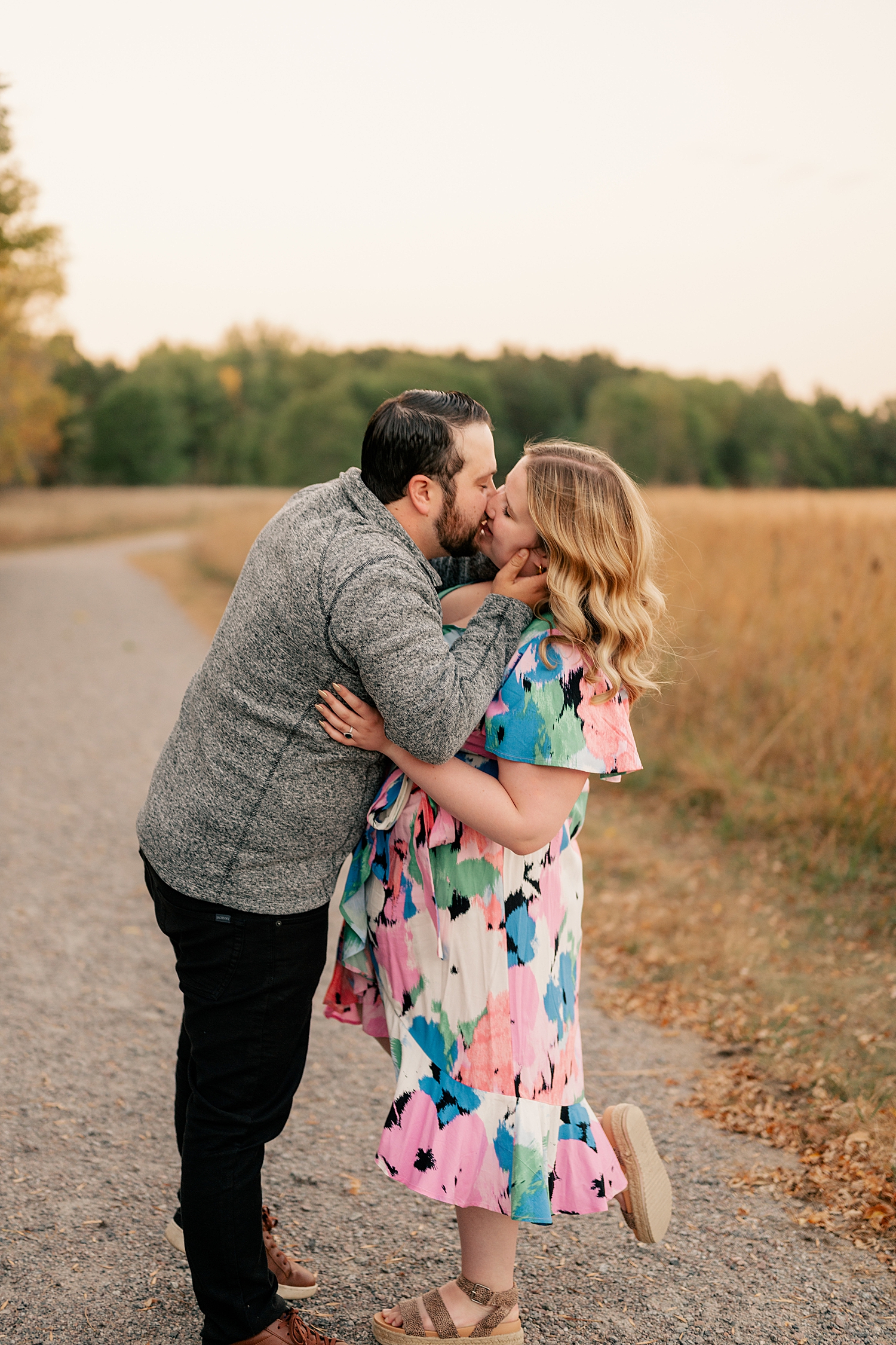 man leans in to kiss woman in colorful dress at Bend in the River Regional Park