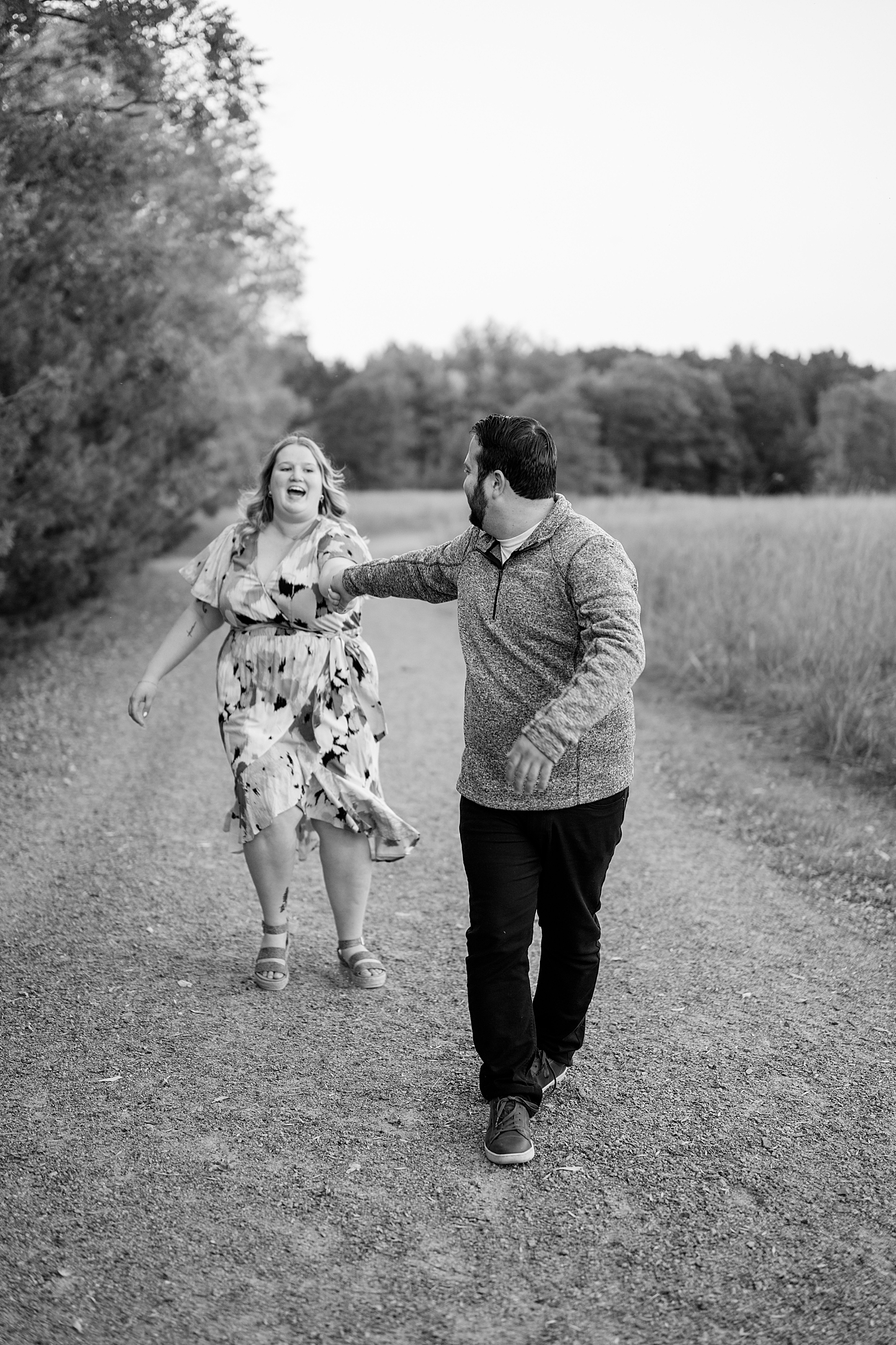 man and woman run down pathway outside by Minnesota wedding photographer 