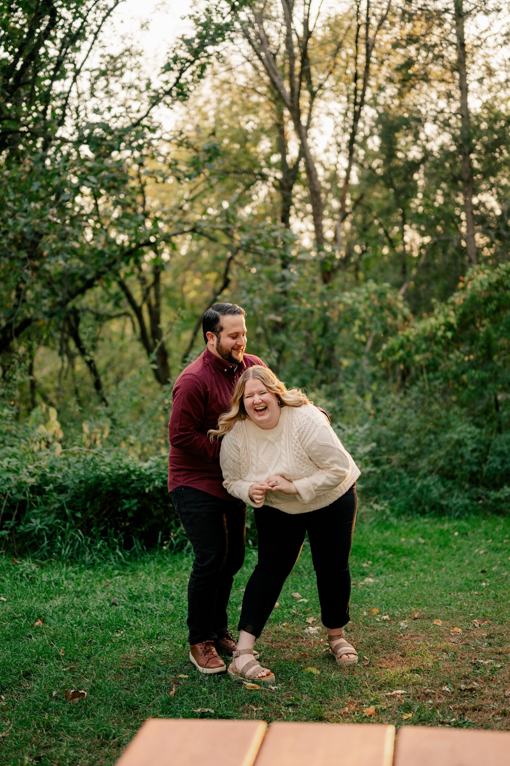 Man tickles fiance in wooded area by Minnesota Wedding Photographer