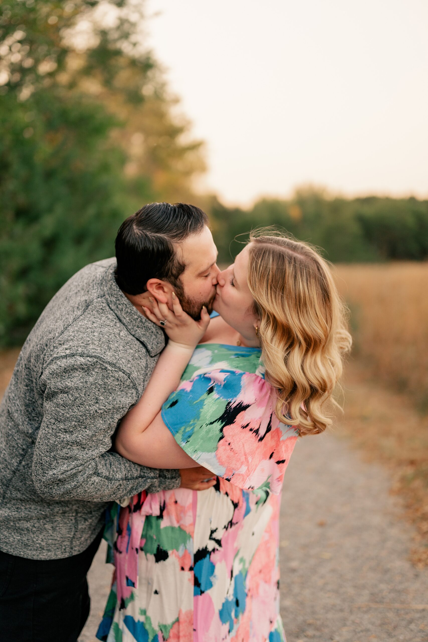 Couple kisses in field in coordinating engagement session oufits