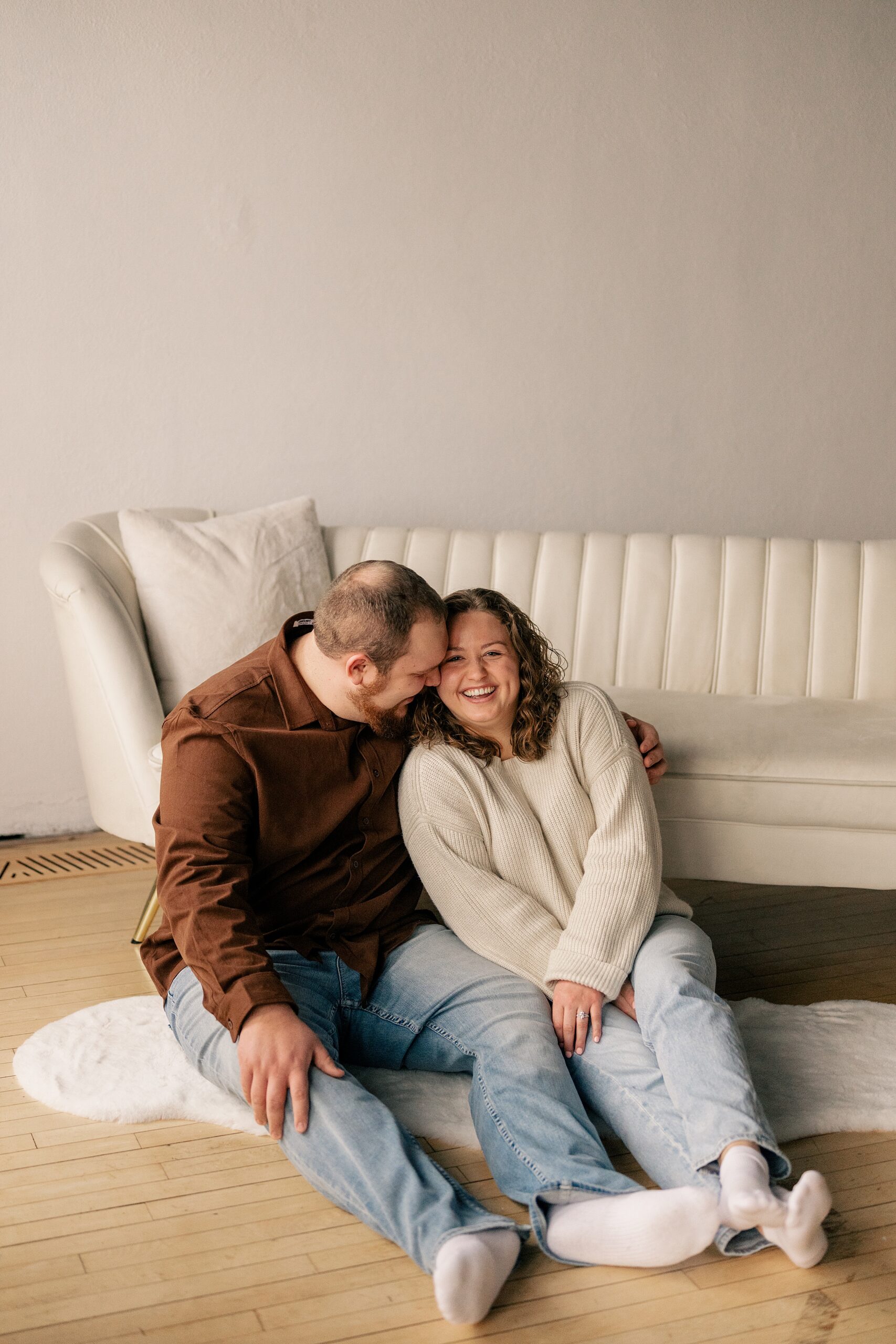 Man snuggles up to fiance in studio in coordinating engagement session outfits