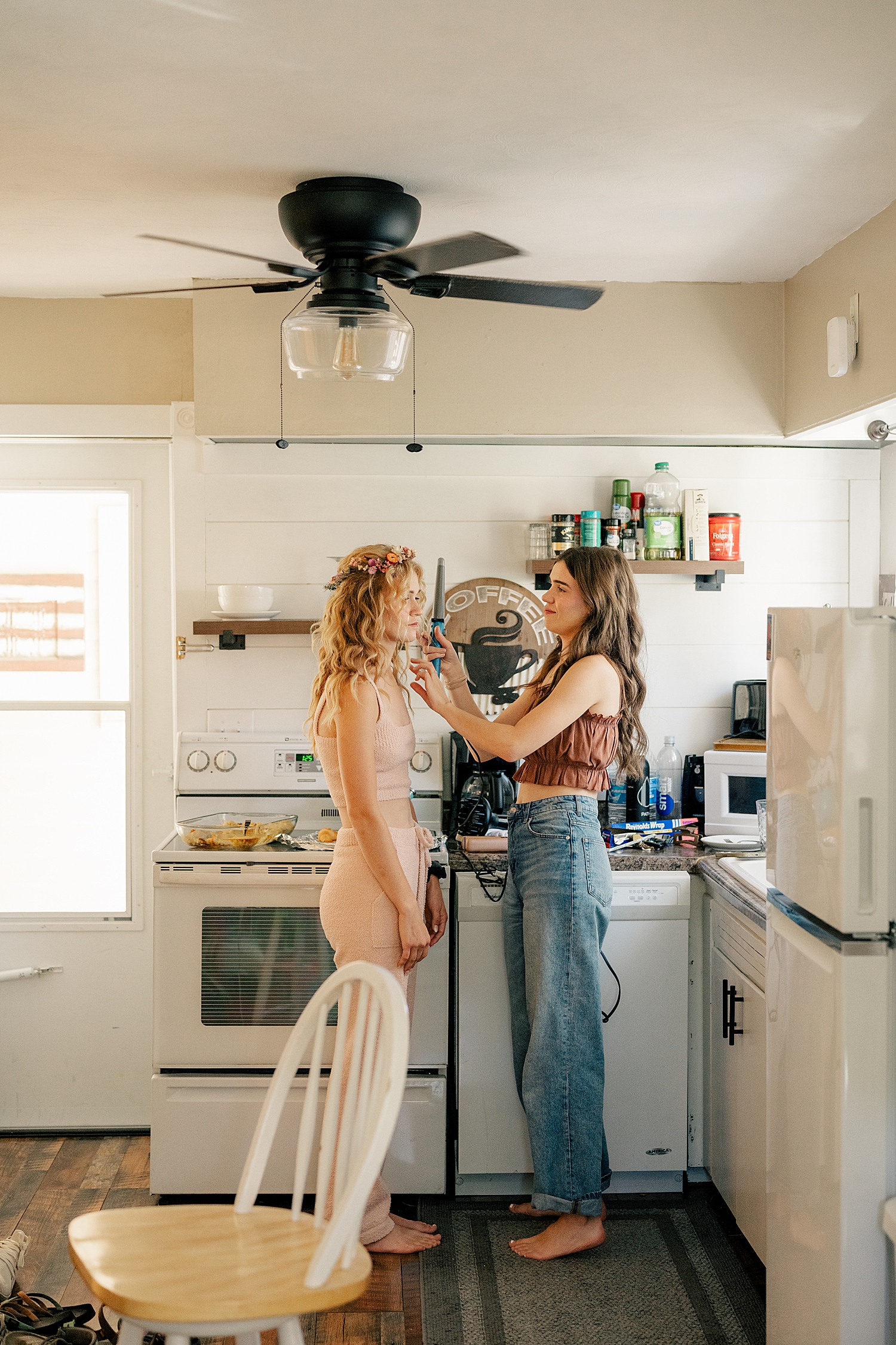 bride gets hair curled by friend in kitchen by Rule Creative Co
