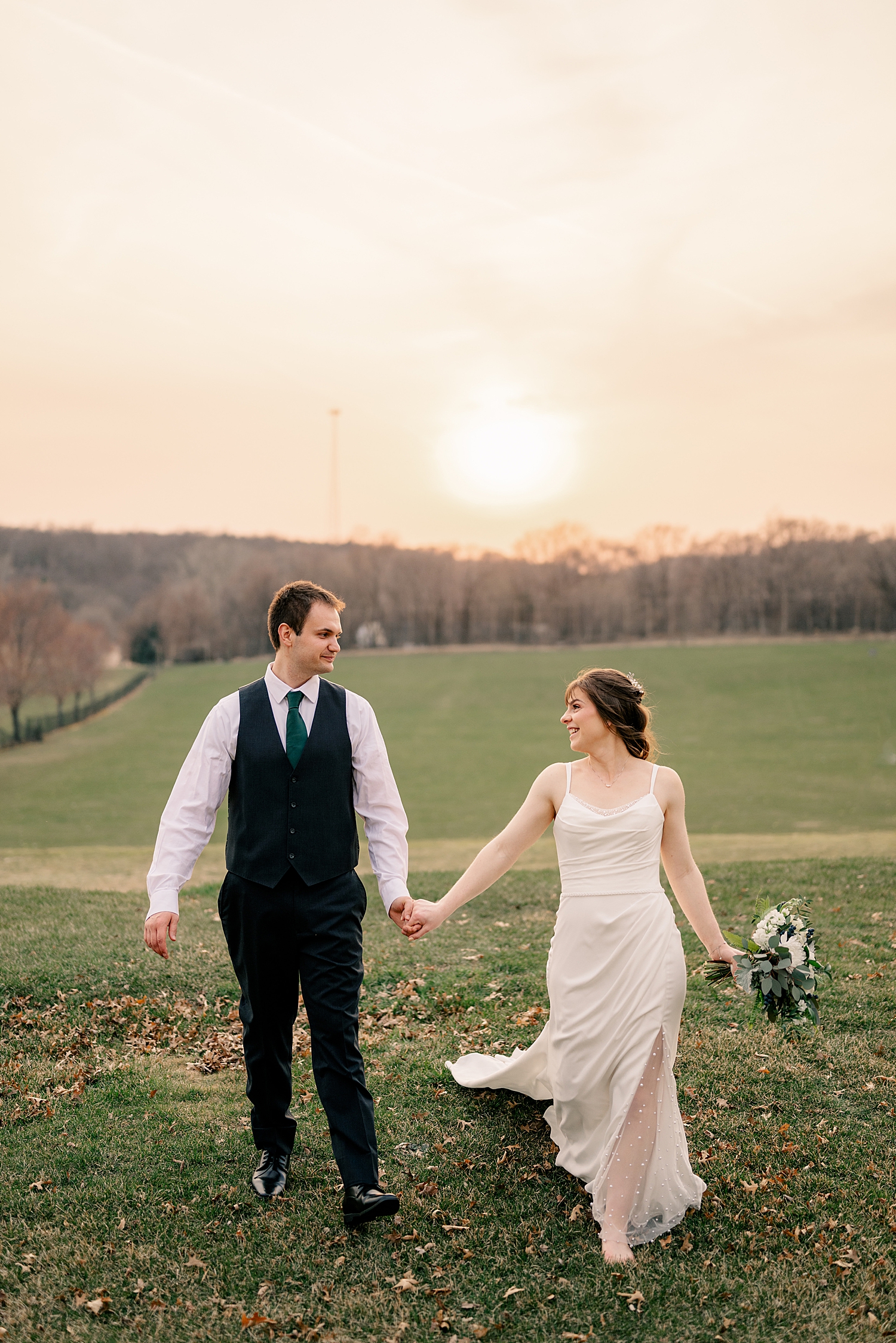couple walks in large field during golden hour by Rule Creative Co