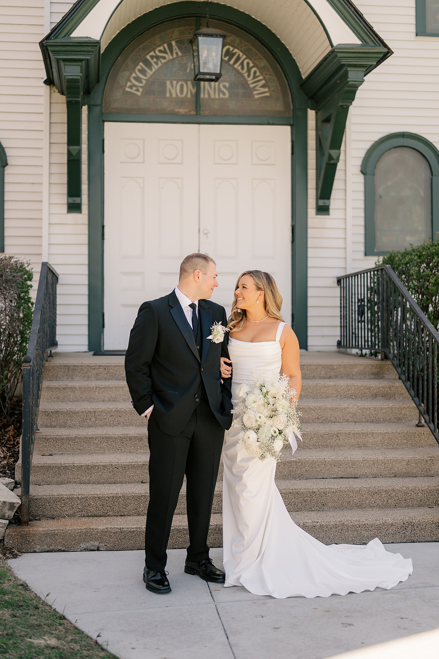 blonde bride looks at new husband outside at Holy Name of Jesus Catholic Community
