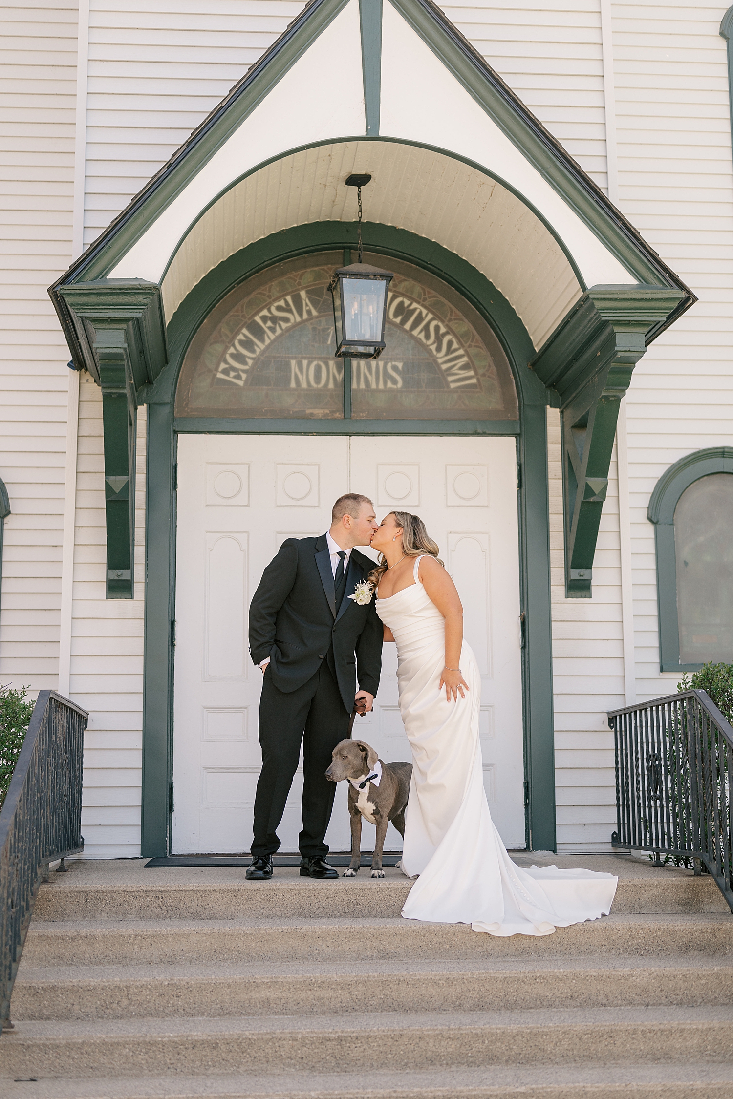 couple kisses over their sweet pup outside by Minnesota wedding photographer