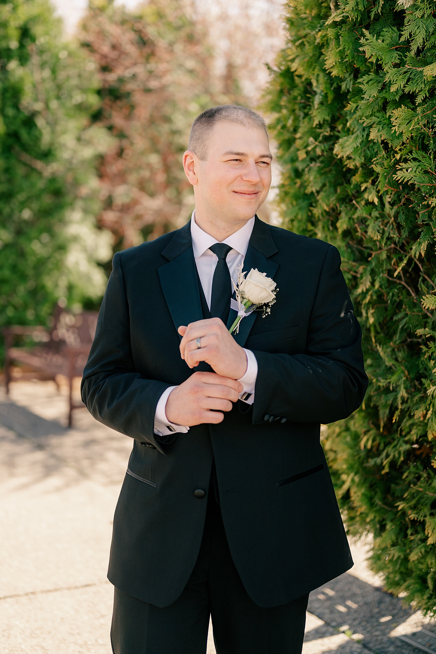 groom adjusts cuffs outside by Minnesota wedding photographer