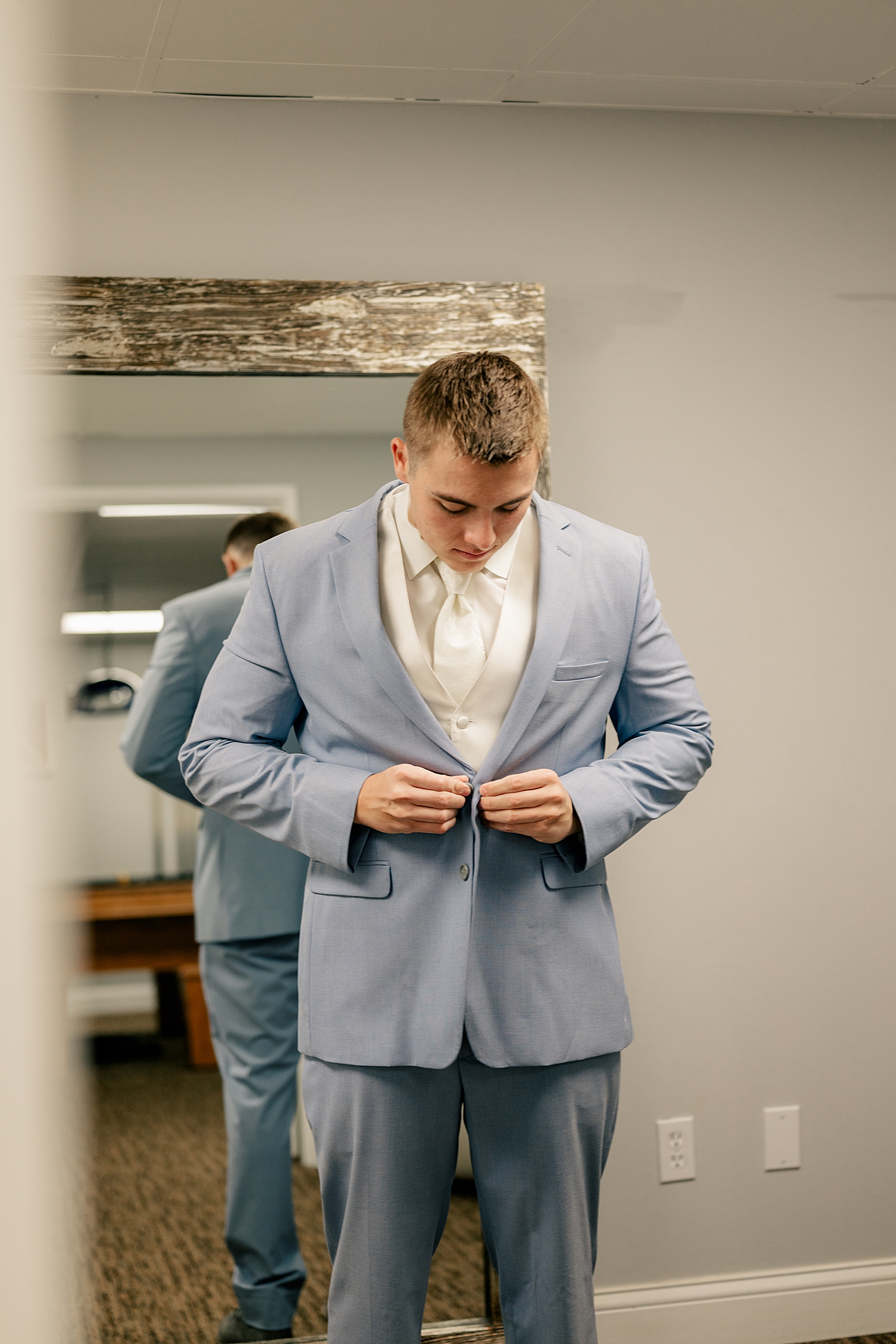 groom buttons his suit at The Grands at Mulligan