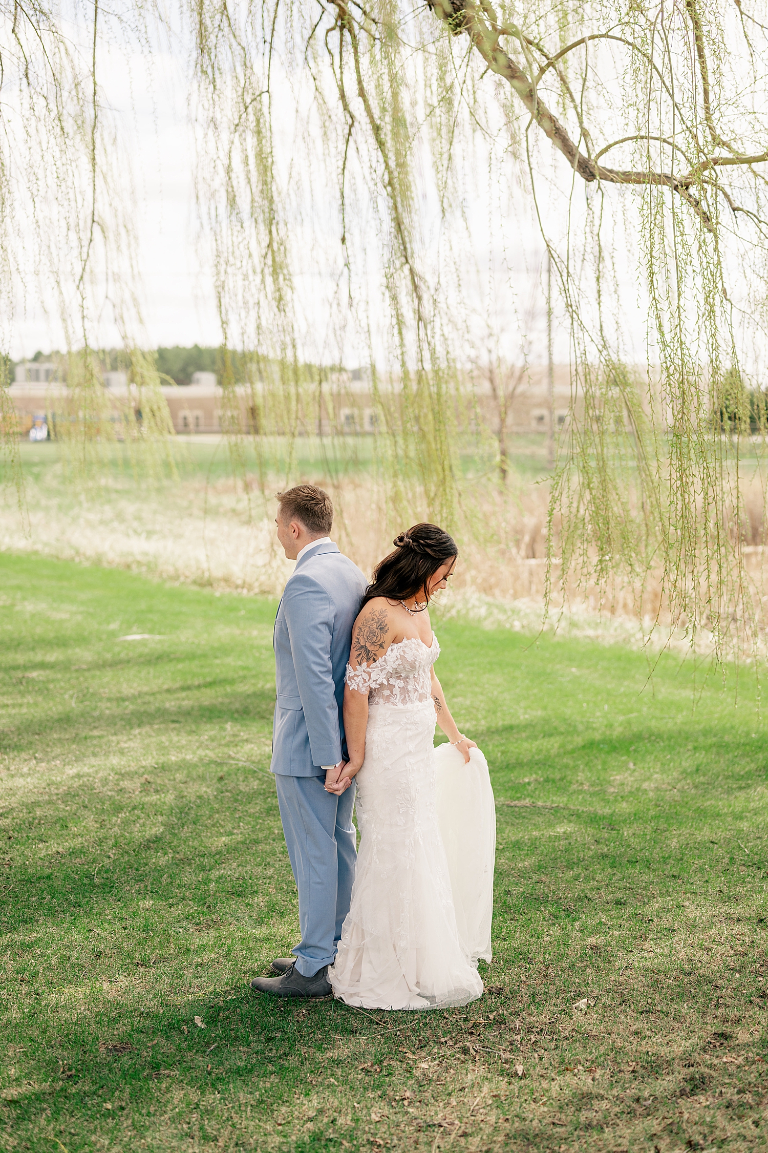 man and woman stand back to back under willow tree by Rule Creative Co