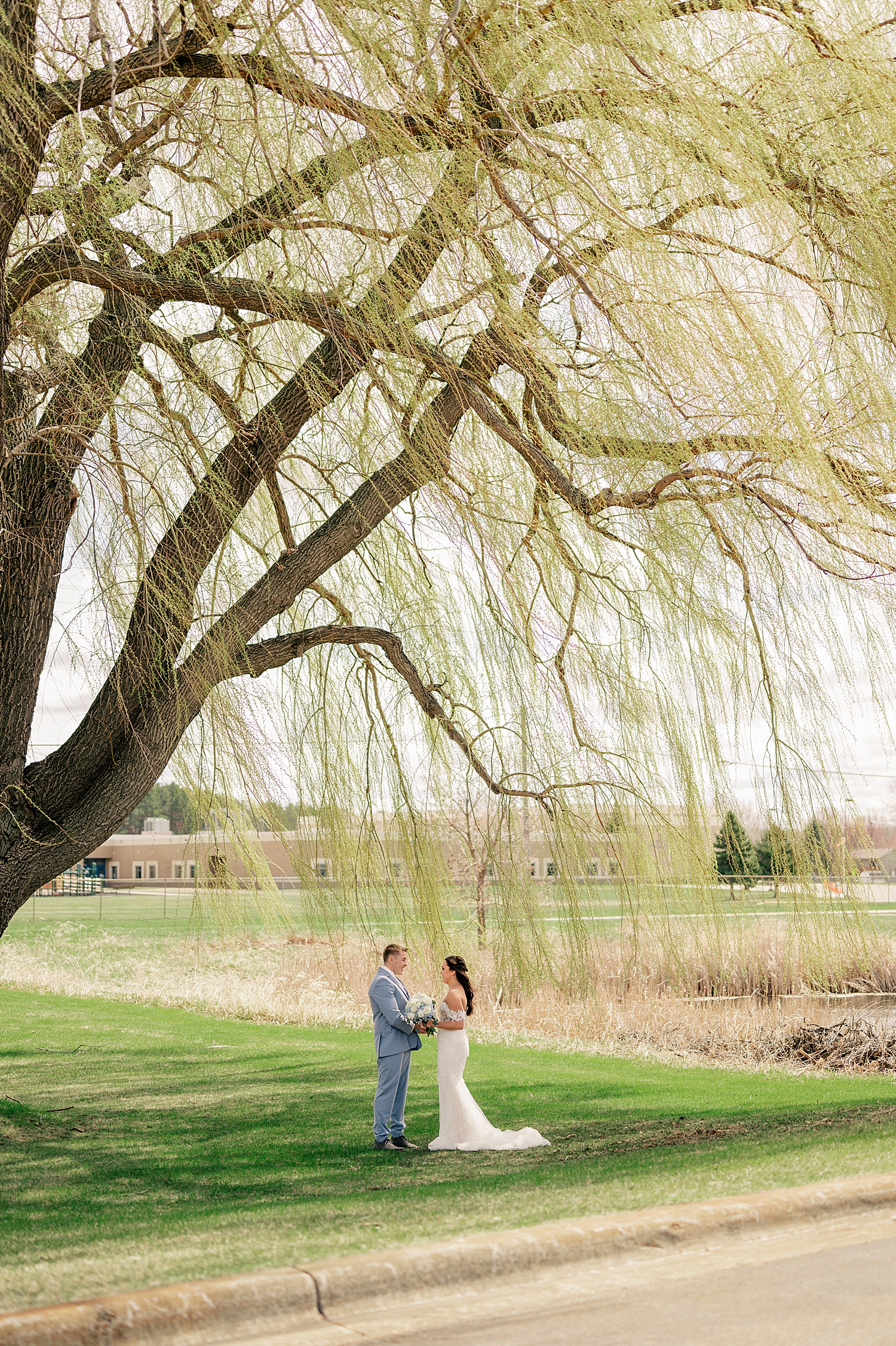 couple stands together under willow tree by Minnesota wedding photographer