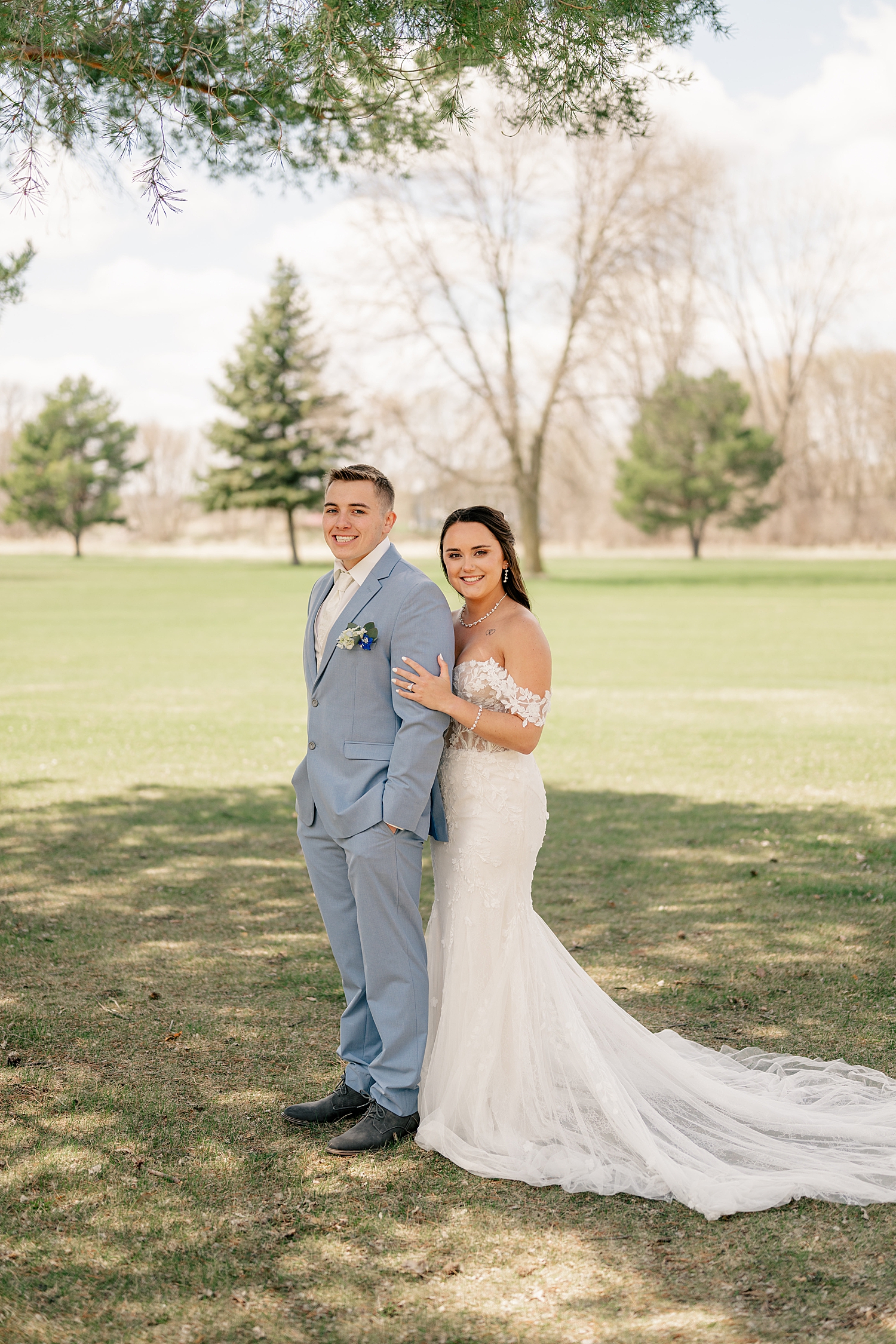 newlyweds grin and embrace under tree at The Grands at Mulligan