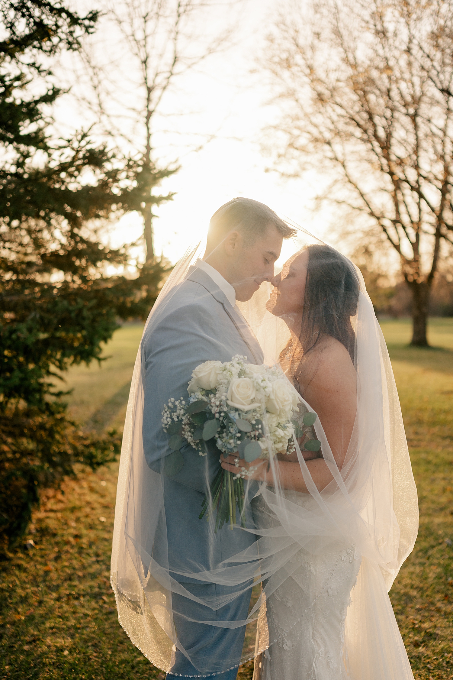 newlyweds covered in veil in golden hour by Minnesota wedding photographer